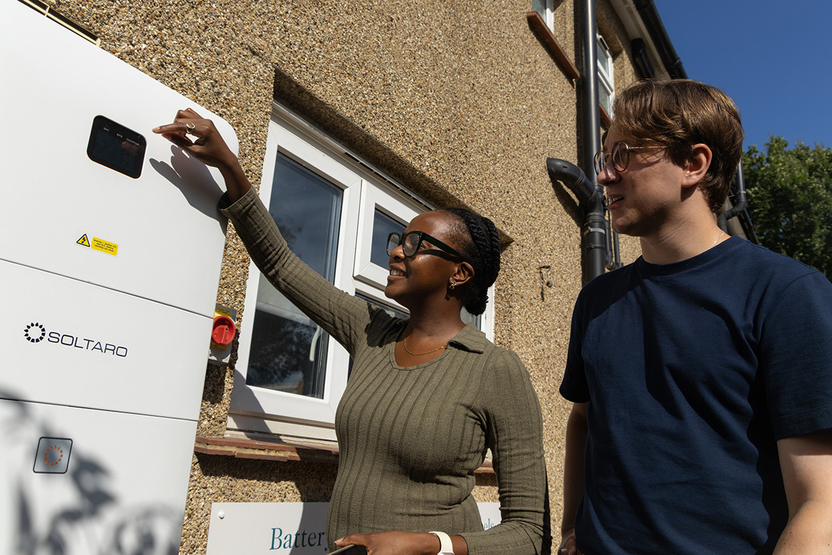 Clarion staff looking at the home battery fitted to the outside wall of the Green Community Home
