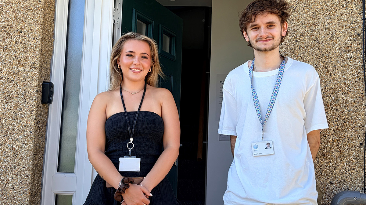 Two Clarion staff members wearing lanyards standing at the front door of the Green Community Home