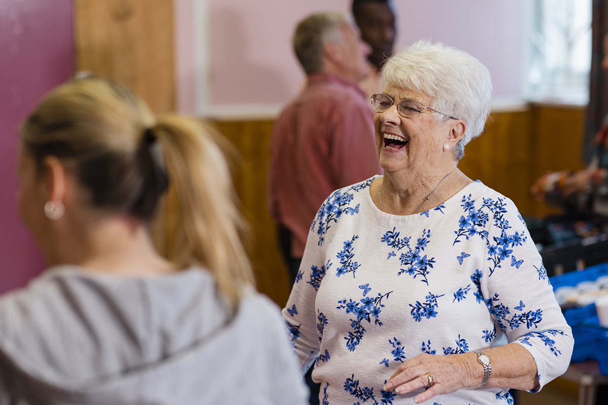 Older woman laughing while chatting with a younger woman at a community event